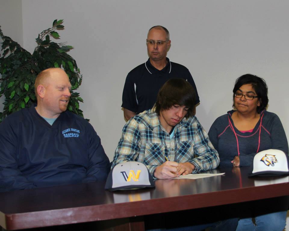 Holman signing his letter-of-intent with, from left, Steve Holman, Jayden Holman, Annie Holman, and rear-standing Mike Jones.