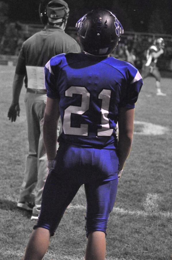 Number 21, Tyler Trout, stands on the sideline of the football field, patiently waiting to get back into the game. 